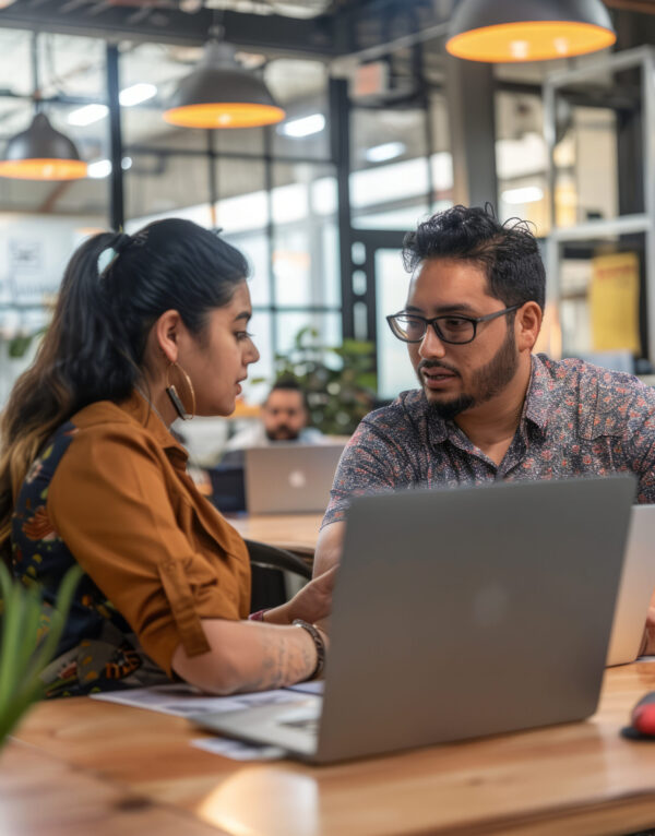 a Hispanic business mentor advising a young entrepreneur in a modern coworking space